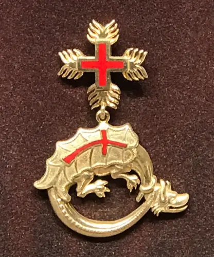 Ejderha Tarikatı’na ait kırmızı haçlı altın madalyonun detaylı görünümü.